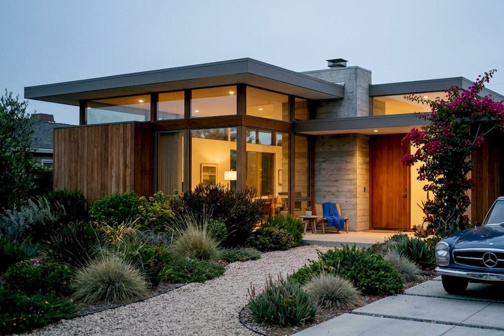 Mid-century modern house exterior with glass walls and garden