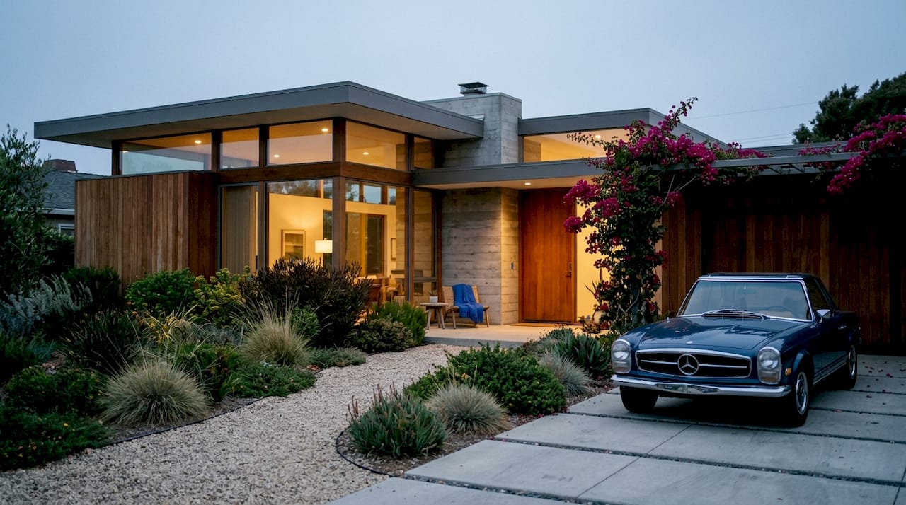 Mid-century modern house exterior with glass walls and garden