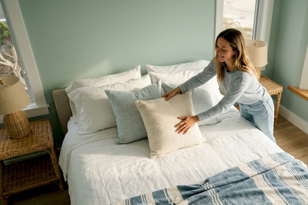 Woman arranging pillows in warm bedroom