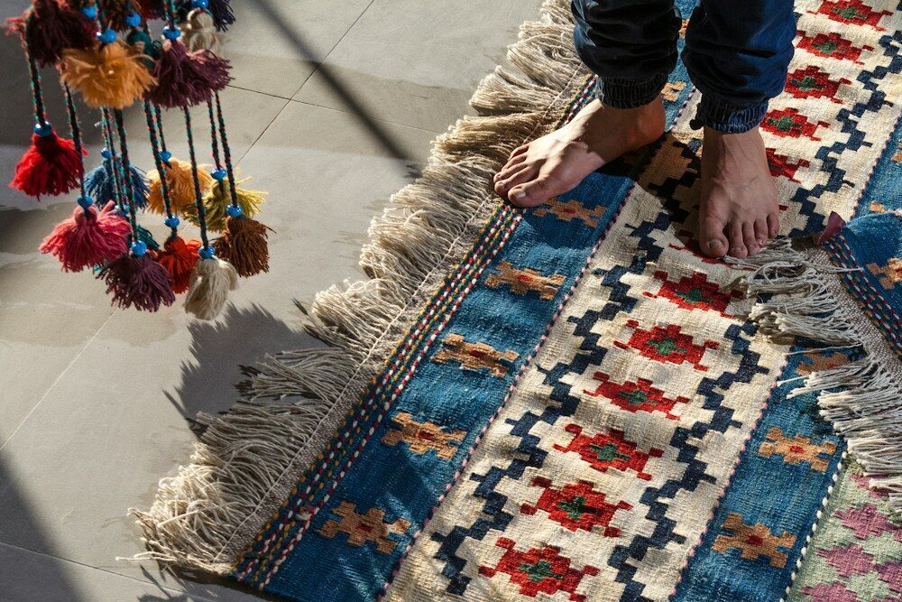 person in blue denim jeans standing on white blue and red area rug