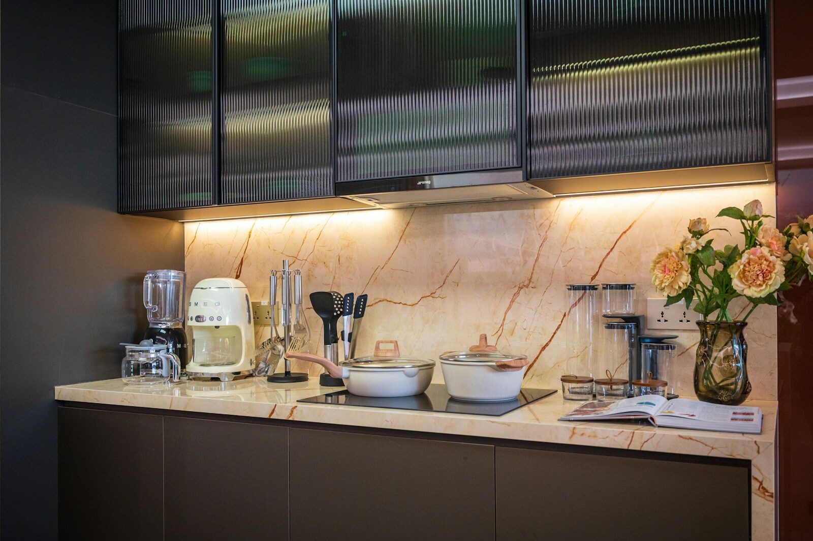 Modern kitchen counter with appliances and flowers.