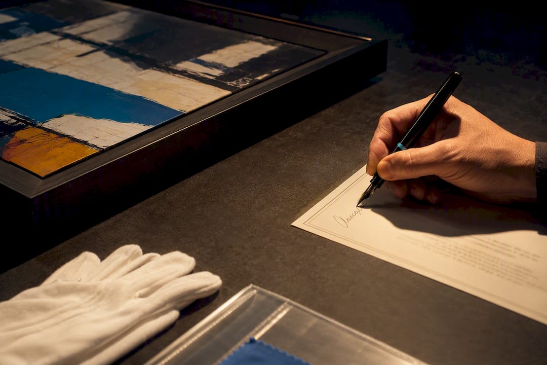 Artist signing certificate beside artwork