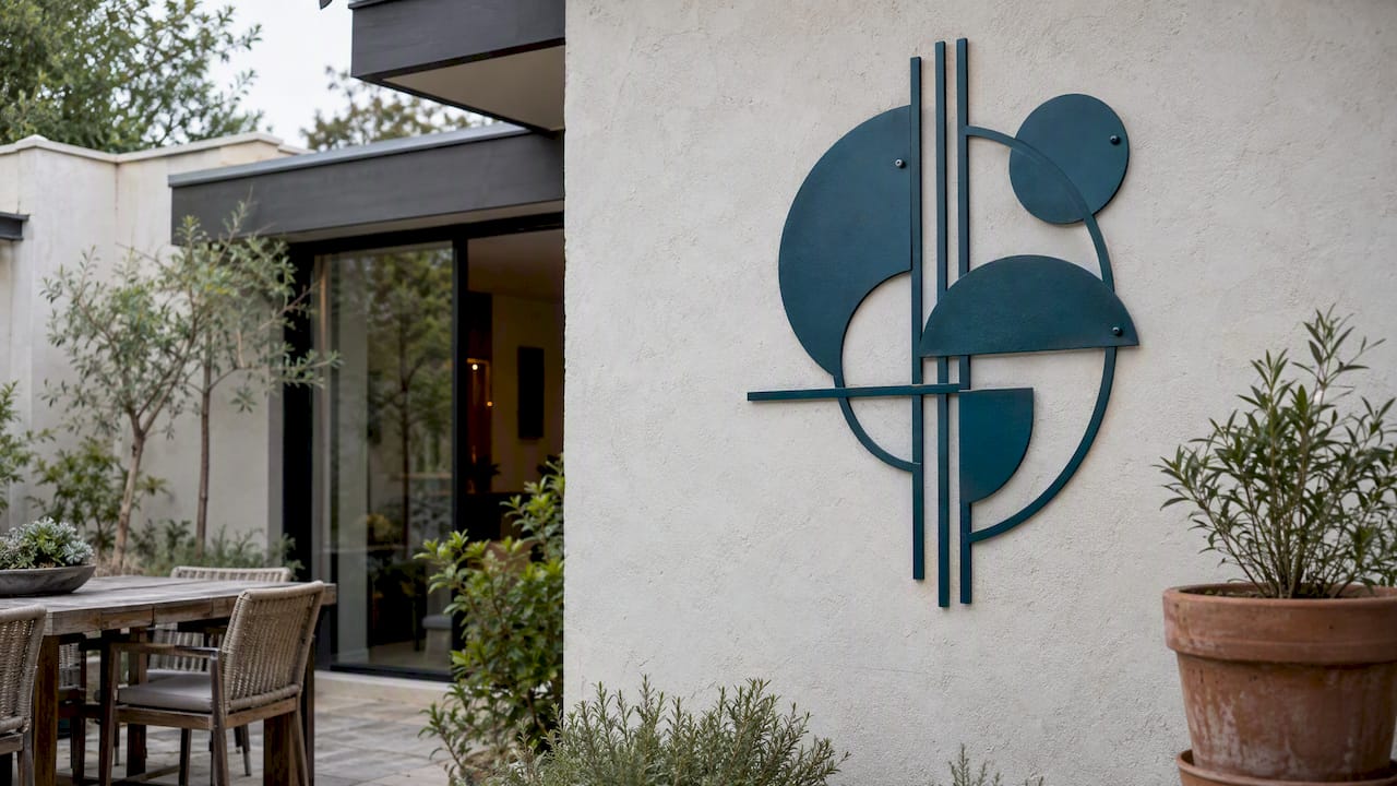 Teal metal sculpture mounted on stucco
