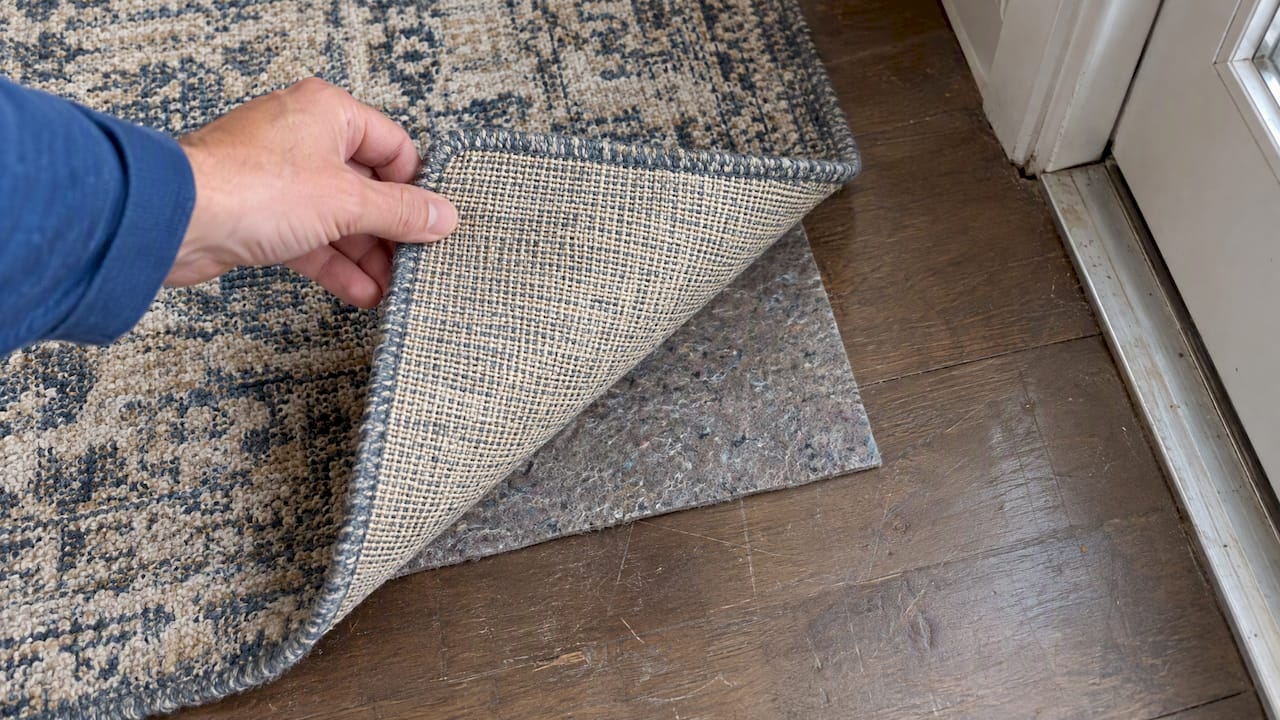 Lifted rug corner revealing its pad