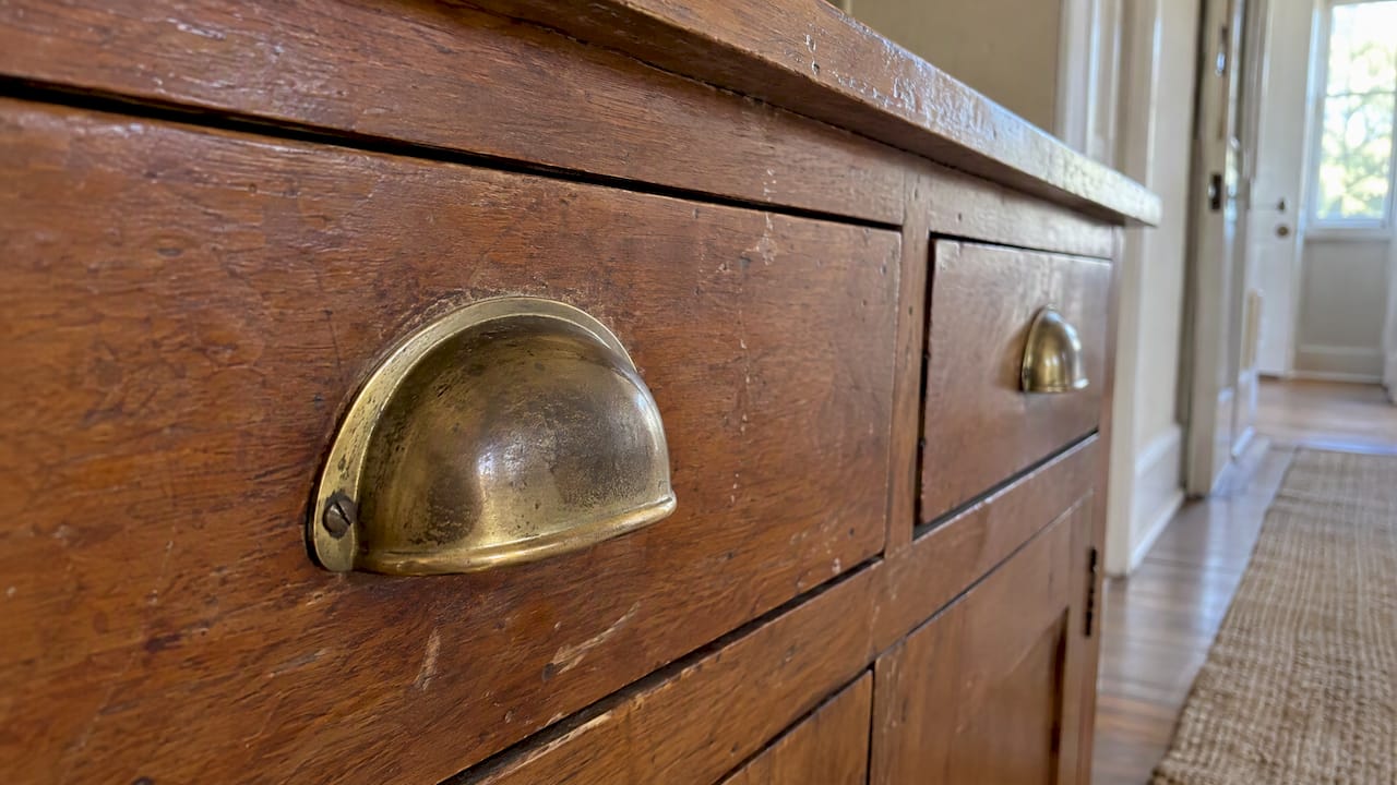Patina darkening on an unlacquered brass drawer pull
