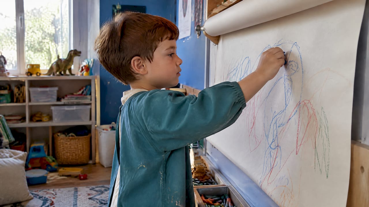 Child drawing on a playroom paper roll
